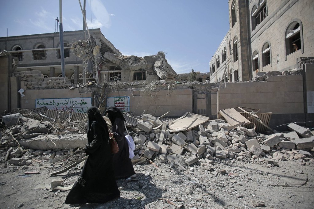 <i> Yemenis walk past rubble after deadly airstrikes in and near the presidential compound, in Sanaa by <a href='https://www.flickr.com/photos/felton-nyc/'>Felton Davis</a> on <a href='https://www.flickr.com/photos/felton-nyc/41162497535'>Flickr</a></i>